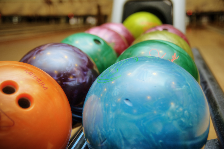 Multi-colored bowling balls at a bowling alley. Shallow DOF, with main focus on blue ball in center.